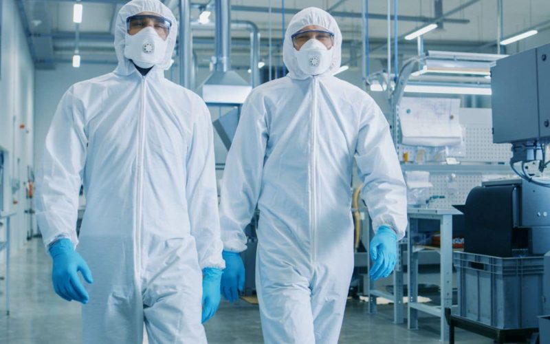 Two,Engineers/,Scientists,In,Hazmat,Sterile,Suits,Walking,Through,Technologically Two Engineers/ Scientists in Hazmat Sterile Suits Walking Through Technologically Advanced Factory/ Laboratory. Clean High-Tech Environment with CNC Machinery.